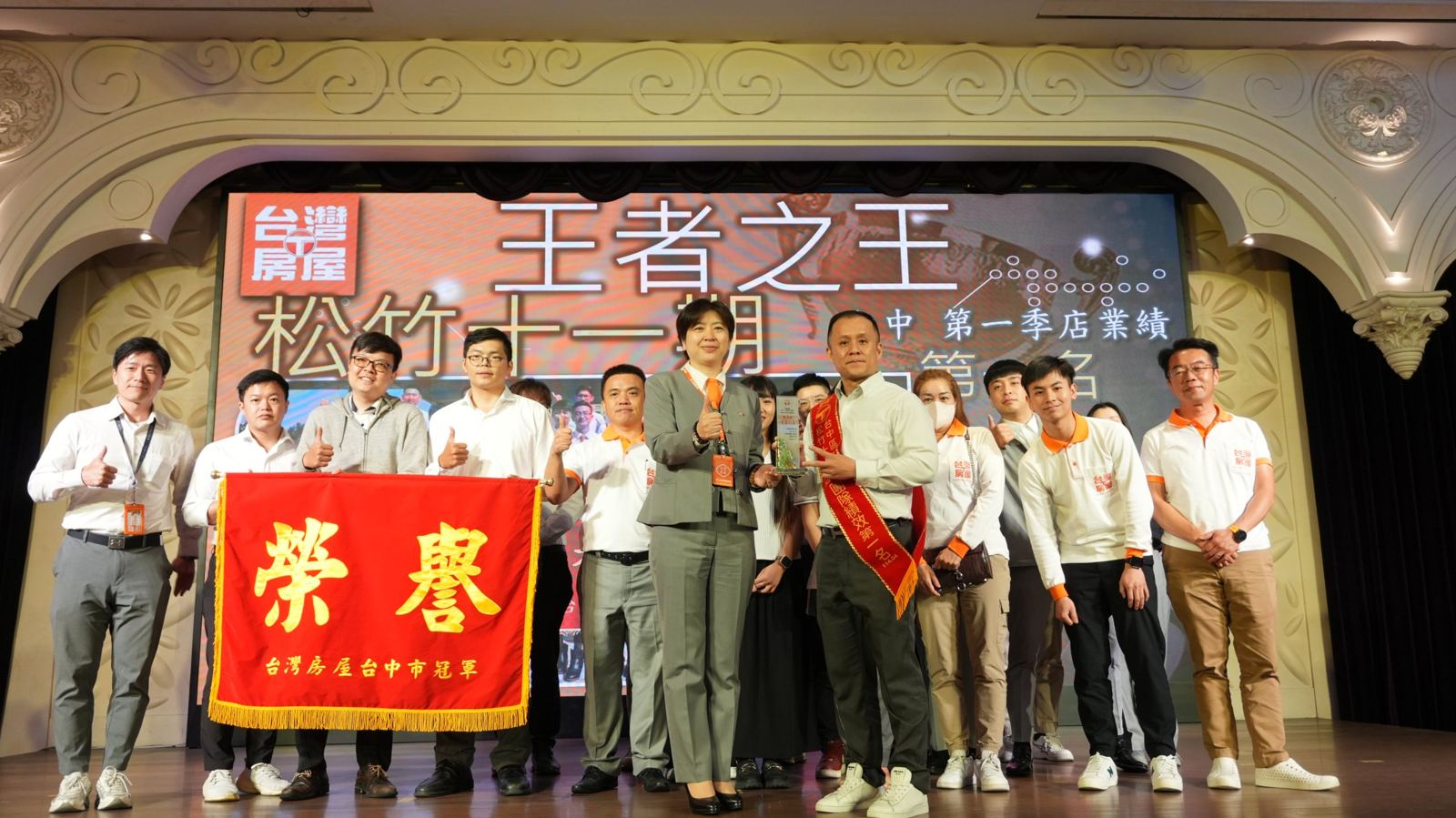 三瀛團隊拿著台灣房屋台中市冠軍榮譽旗在台上合照